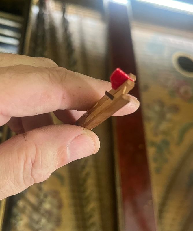 A person is holding a piece of wood with a red button on it.