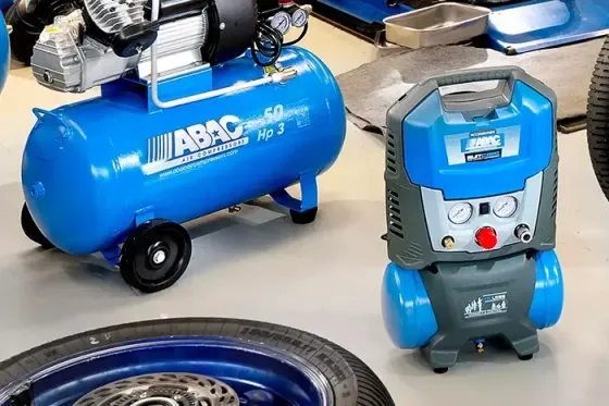 In un'officina si trova un compressore d'aria blu, accanto al quale ce n'è uno più piccolo, blu e grigio.