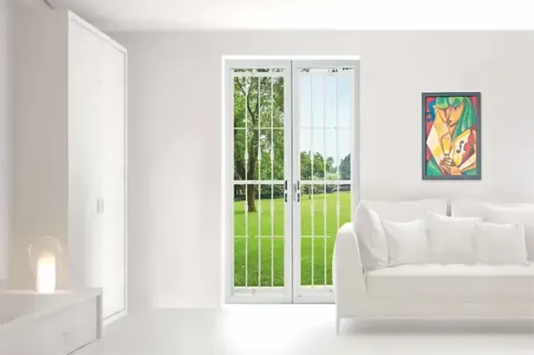 Soggiorno minimalista bianco con porte a vetri, vista sul prato verde, divano bianco e quadri colorati alle pareti.
