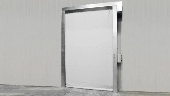 Porta metallica bianca in un corridoio grigio, leggermente socchiusa con serratura visibile sul lato destro.
