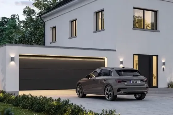 Casa moderna bianca al crepuscolo con un SUV grigio parcheggiato nel vialetto.