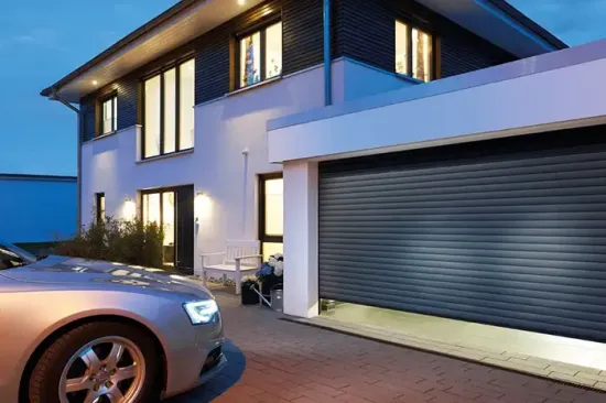 Casa moderna a due piani al crepuscolo, con garage illuminato e auto argentata parcheggiata nel vialetto.