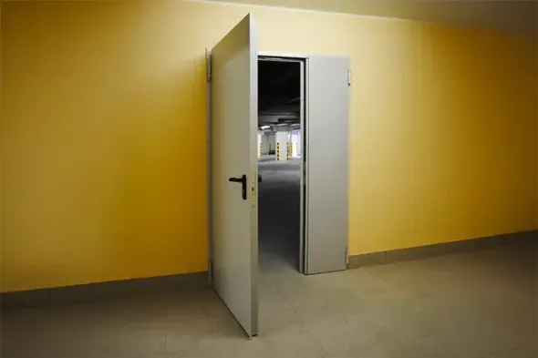 Una porta bianca si apre in un corridoio giallo, rivelando una stanza buia all'interno.