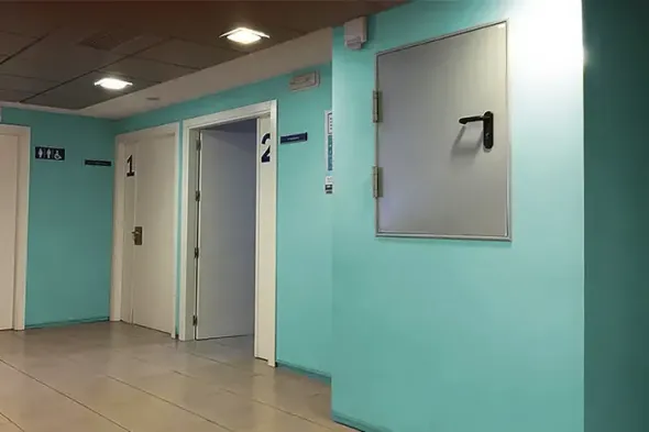 Corridoio turchese con porte dell'ascensore e corrimano a muro.