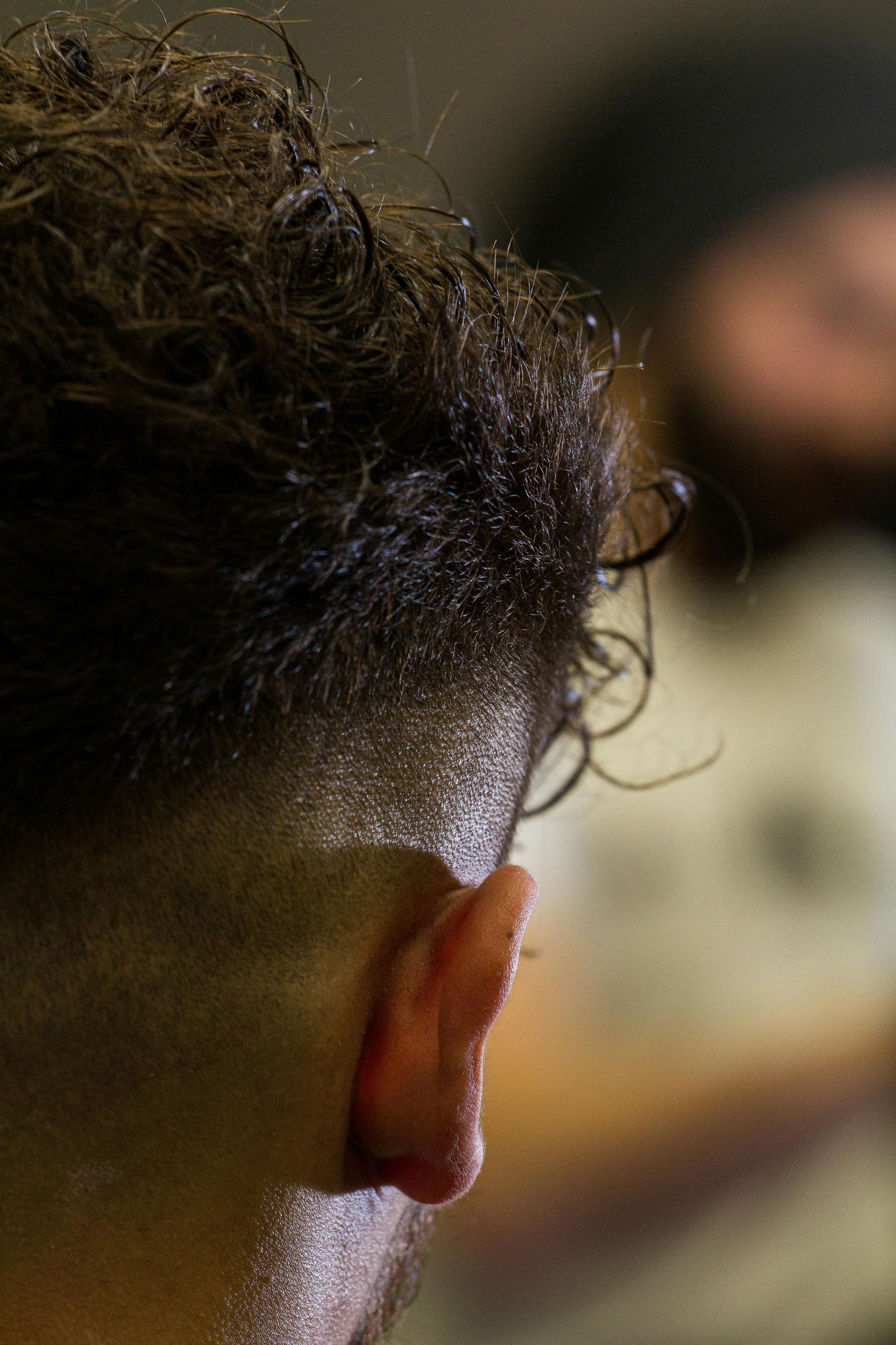 Close-up of the back of a person’s head with curly hair in a blurred indoor setting