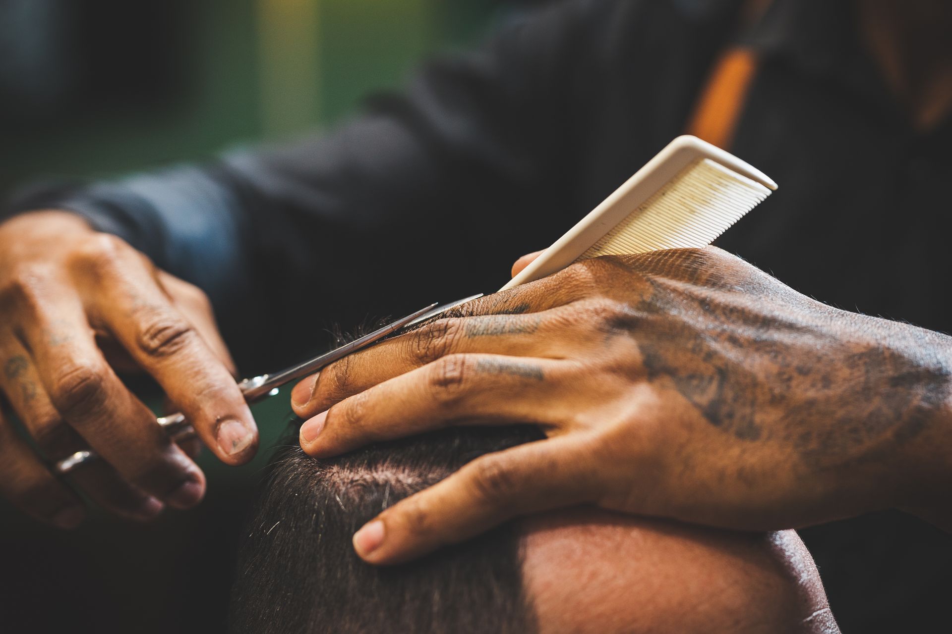 Hands combing a person’s hair with a white comb in a close-up salon scene