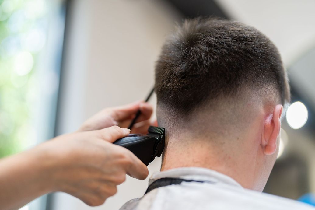 Person getting a haircut with electric clippers at a barbershop