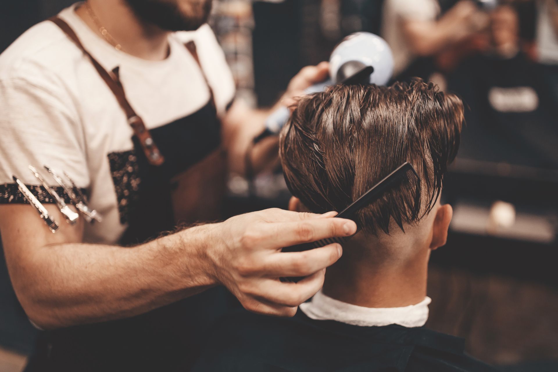 Hair stylist combing and cutting a client’s hair in a barbershop