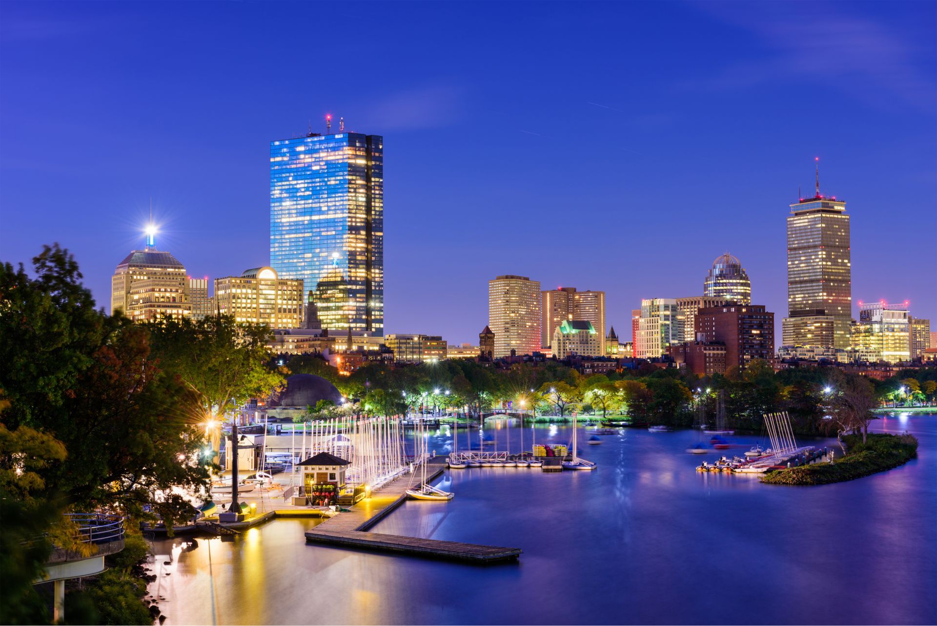 A city skyline at night with a body of water in the foreground.