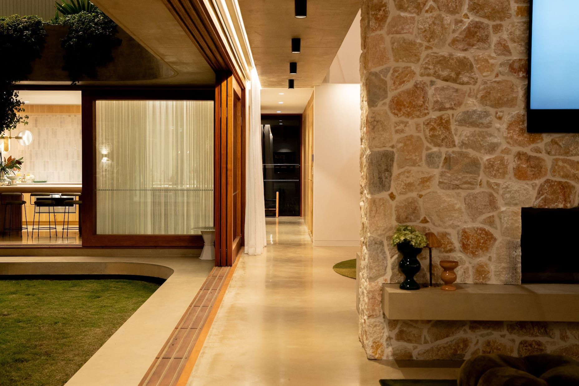 Open doorway to a living space and a hallway. Stone wall and concrete floors.