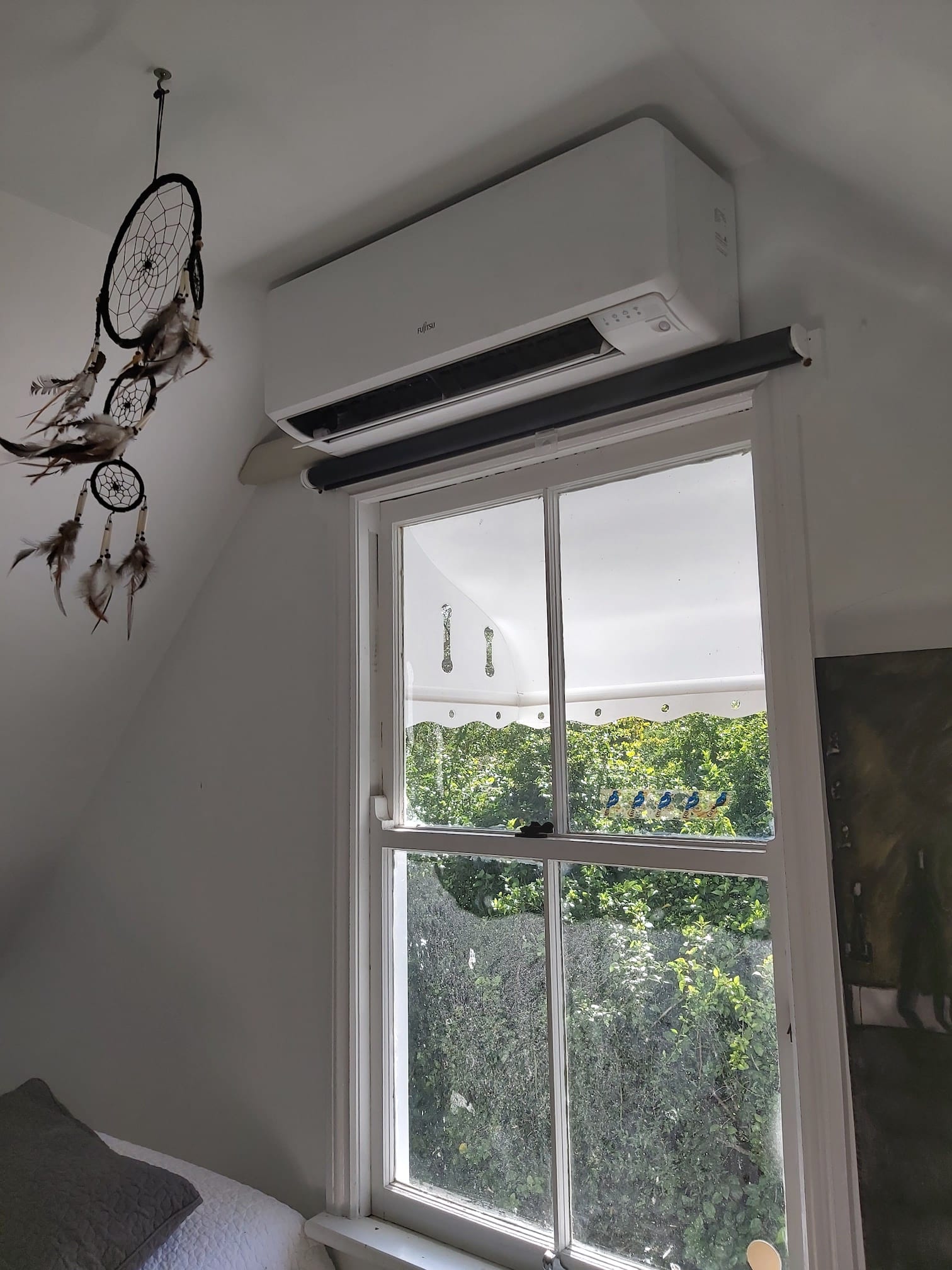 There is a dream catcher on the wall above the window.