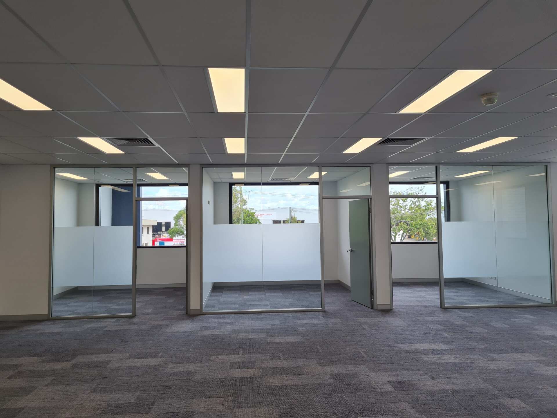 A large empty office with a lot of windows and a carpeted floor.