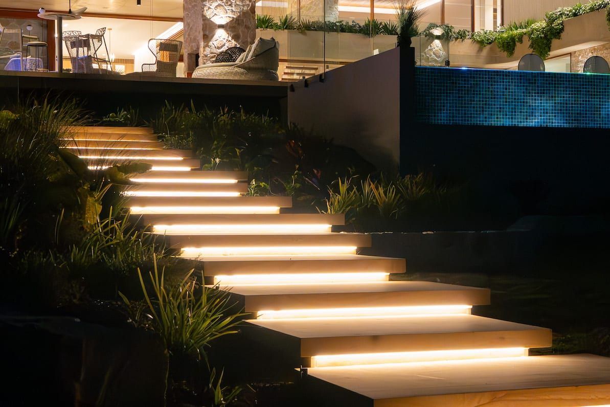 Lit outdoor stairs at night next to a dark pool.