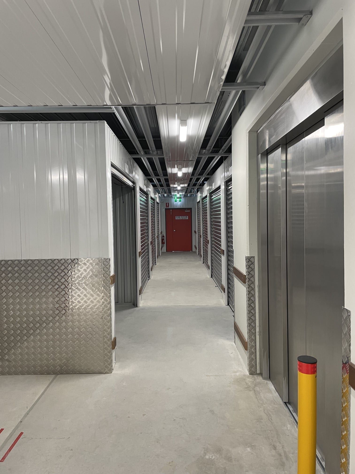 A long hallway with stainless steel walls and a red door