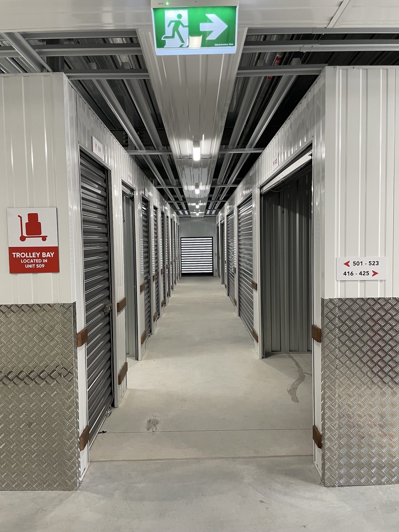 A long hallway with a green exit sign on the ceiling.