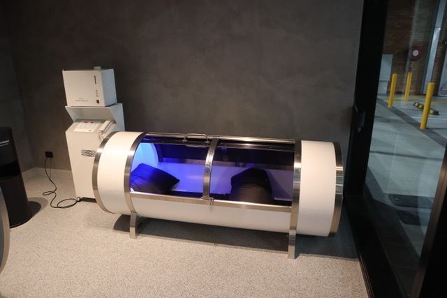 A person is laying in an oxygen chamber in a room.