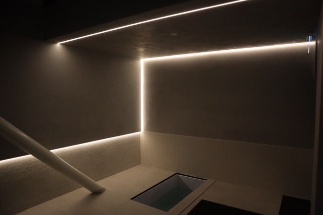 A room with a staircase and a sink and a light on the wall