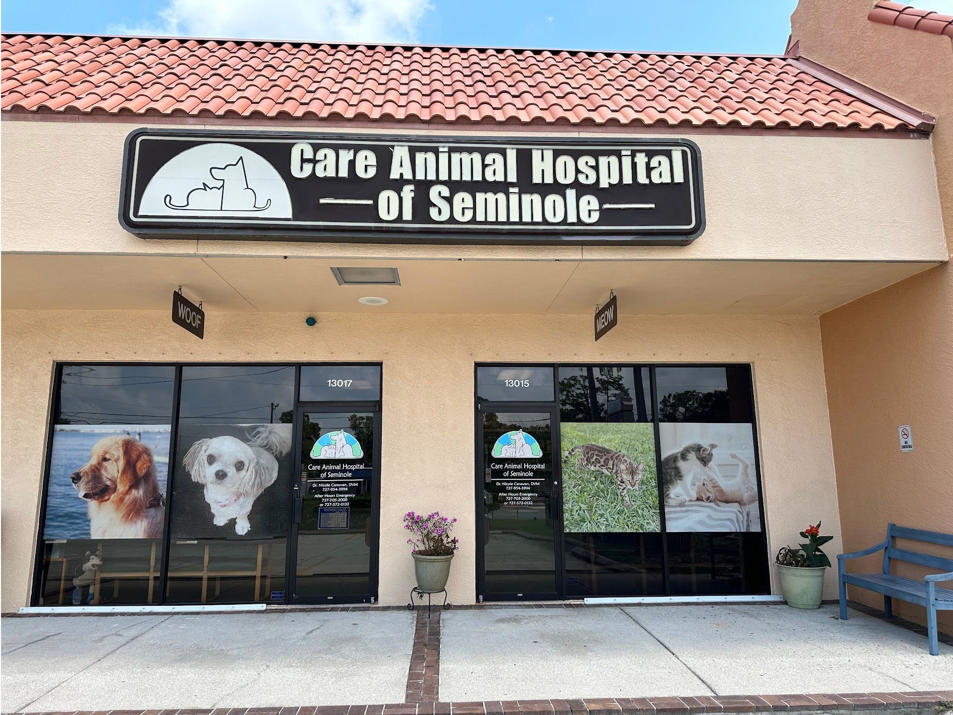 A veterinarian 's office with a table , cabinets , sink and paintings on the wall.