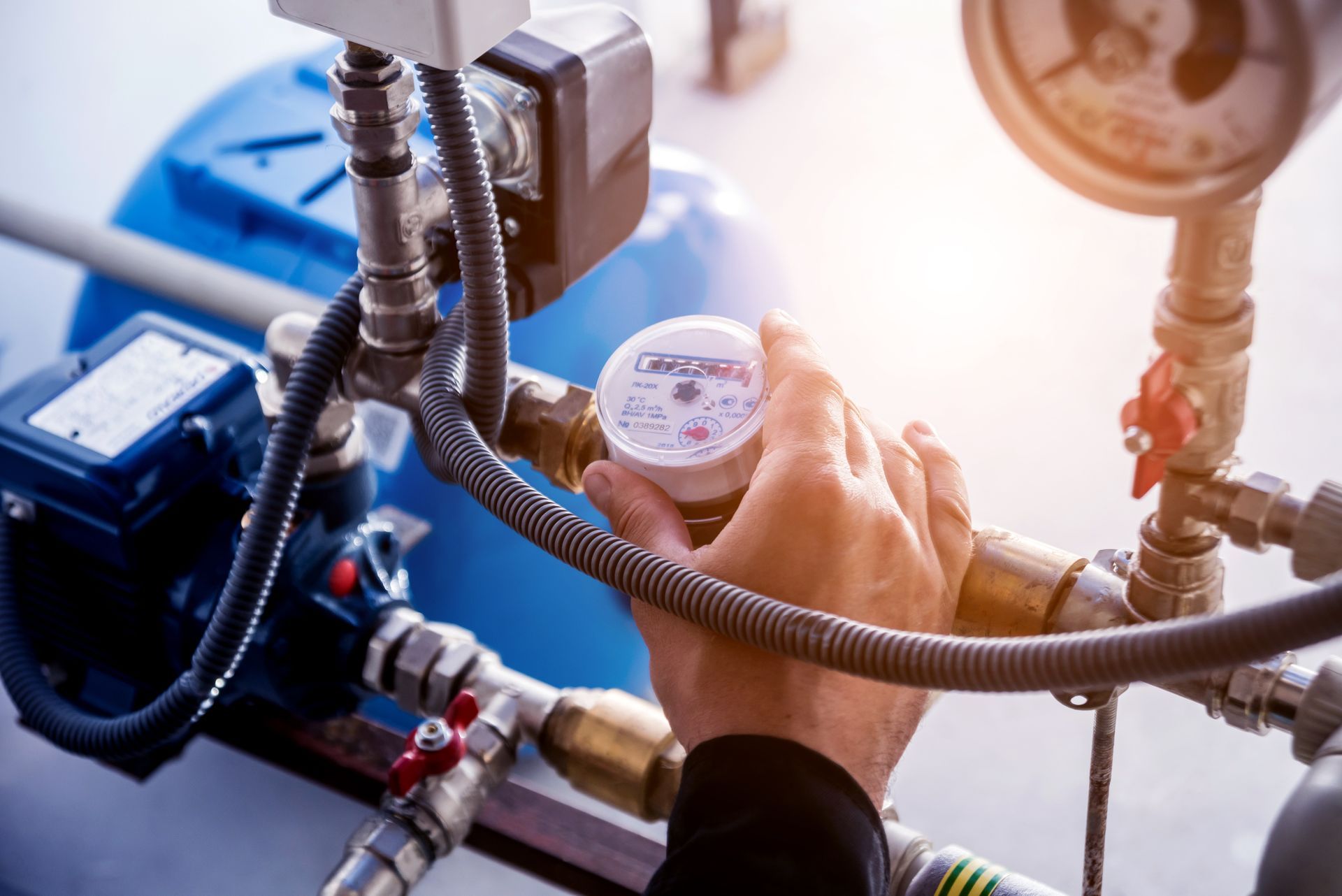 Hand adjusting a pressure gauge on a pump system with connected pipes and valves. Hand adjusting a pressure gauge on a pump system with connected pipes and valves.