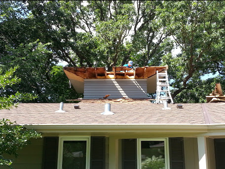 a man is working on the roof of a house .
