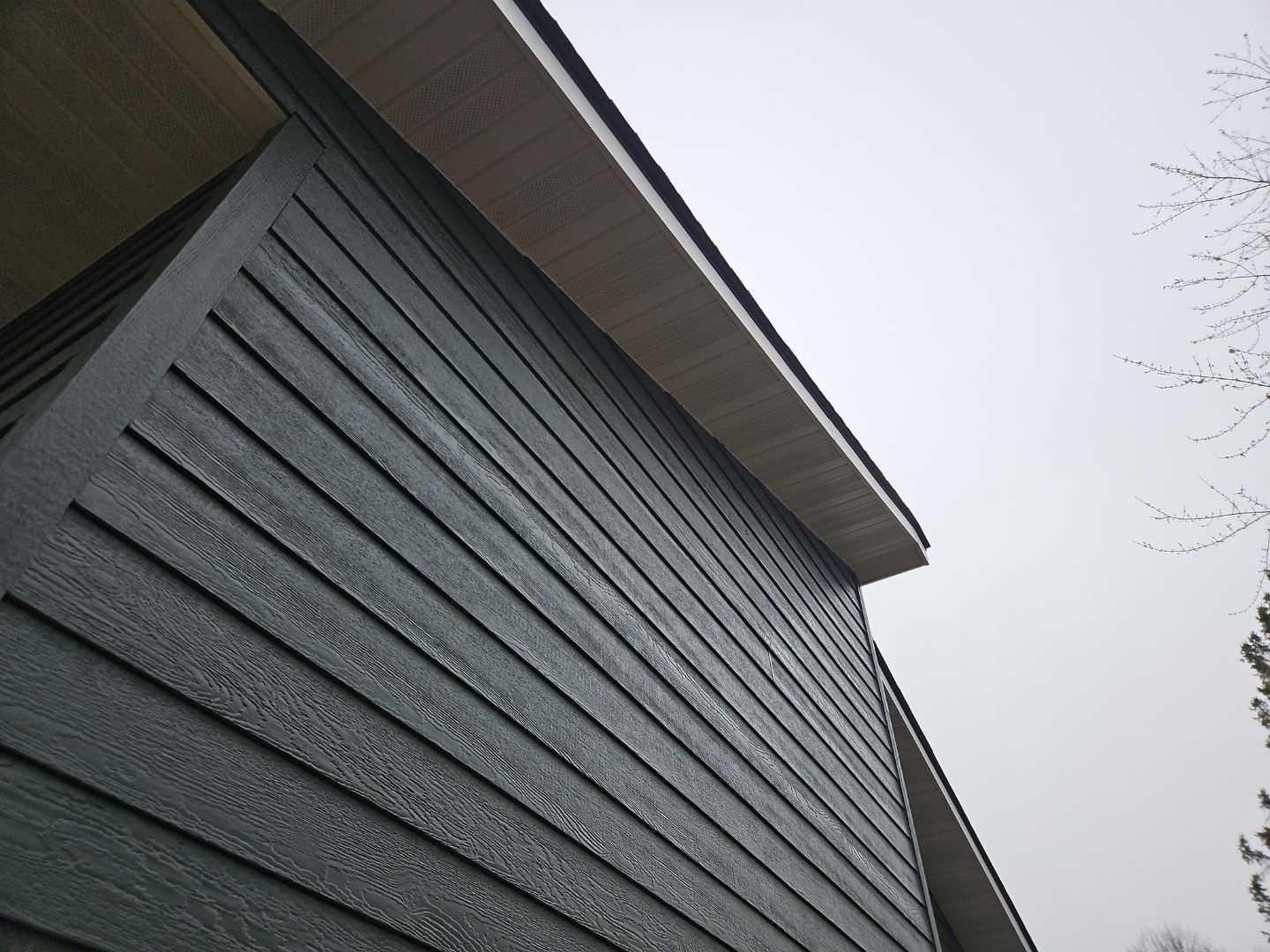 looking up at the side of a house with a tree in the background