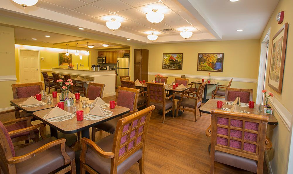 Cozy restaurant dining room with set tables, upholstered chairs, warm lighting, and wall art