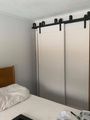 Bedroom with white sliding closet doors on black hardware beside a bed with white bedding