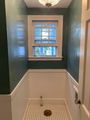 Small bathroom with teal walls, white wainscoting, a window, and a patterned shower floor with drain.