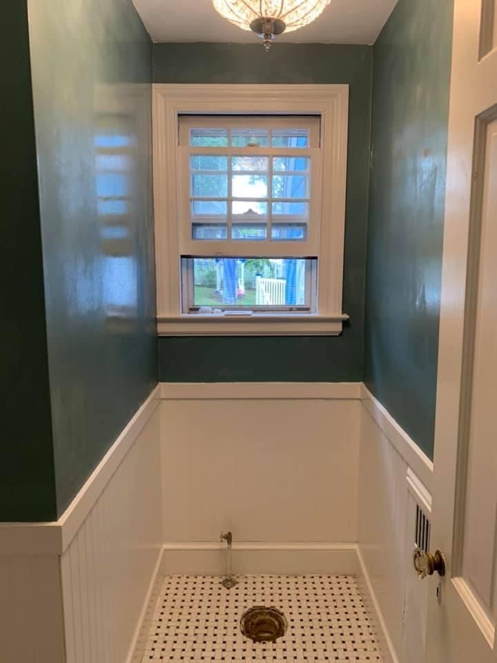 Small bathroom with teal walls, white wainscoting, a window, and a patterned shower floor with drain.