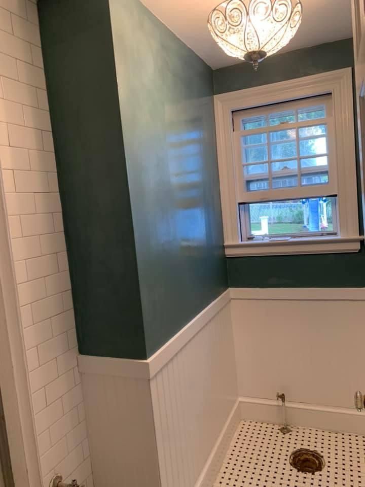 Small bathroom with white tile, dark green walls, a window, and a shower drain in the floor.