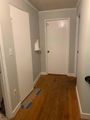 Narrow hallway with gray walls, white doors, wood floor, and blue painter’s tape on the floor