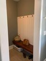 Small entryway nook with bench, wall hooks, baskets, and shoes on the floor.