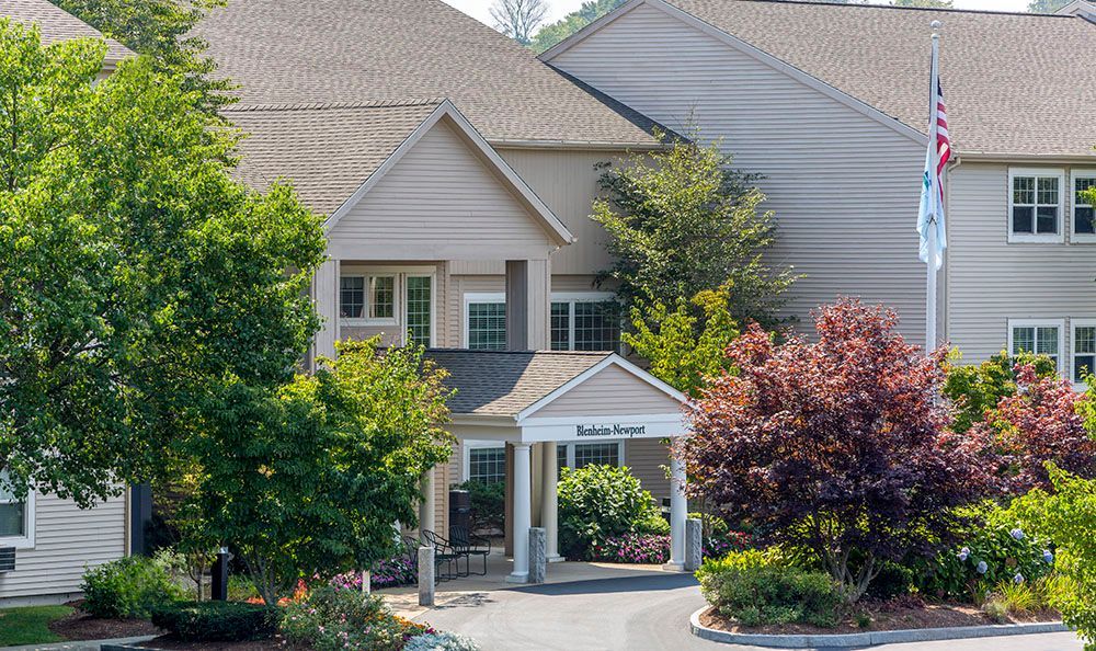Apartment building entrance with white awning, trees, and an American flag