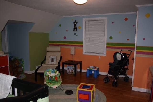 Colorful child’s playroom with toys, stroller, chairs, and a window on striped walls