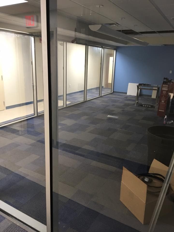 Empty office space with glass walls, blue accent wall, and carpeted floor
