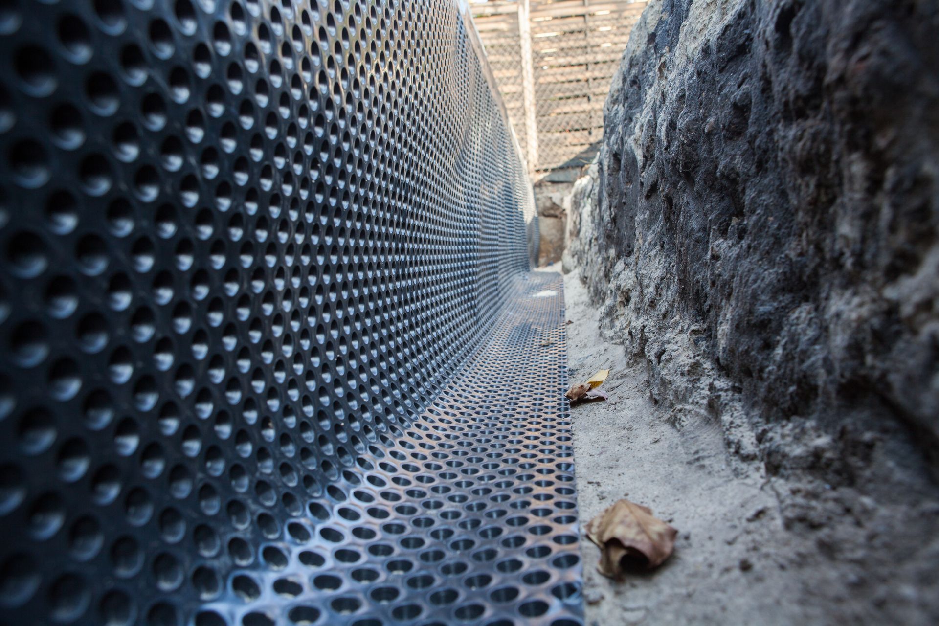 Un système de drainage est en cours d'installation sur un mur en béton.