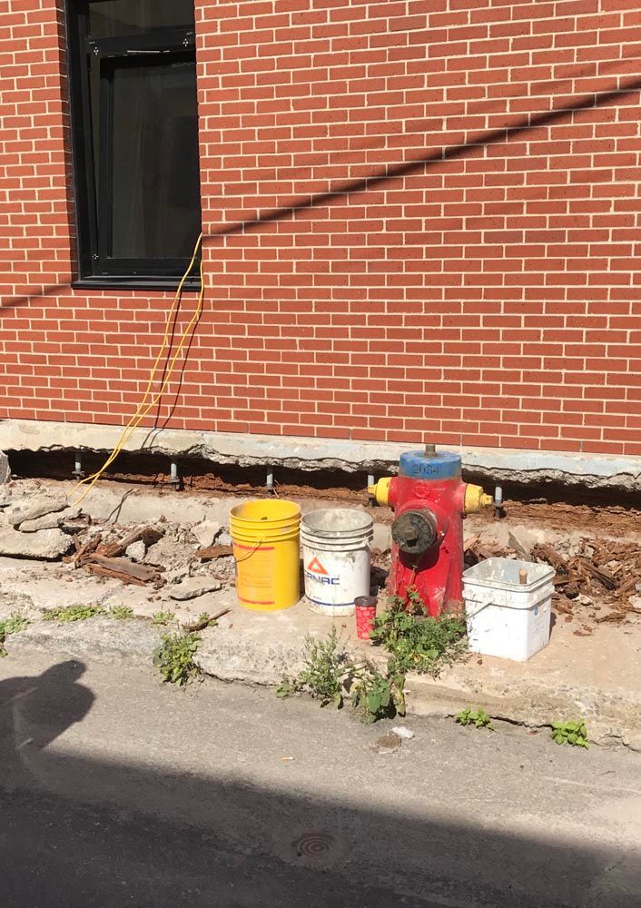 Une bouche d'incendie rouge se trouve devant un bâtiment en briques