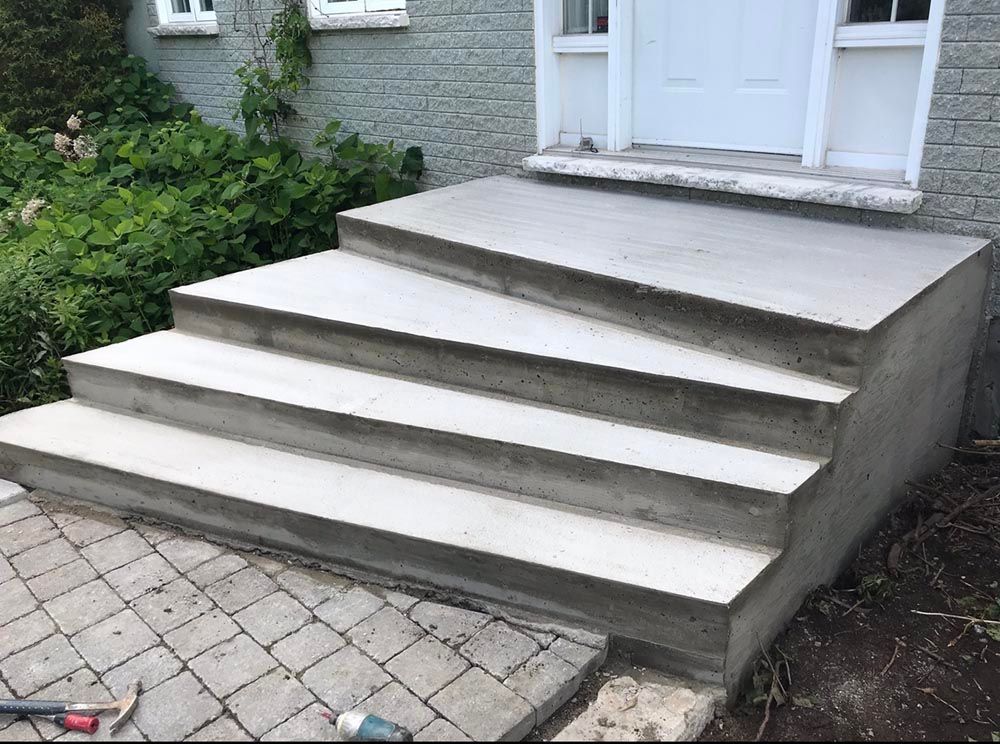 Un escalier en béton est en cours de construction devant une maison.