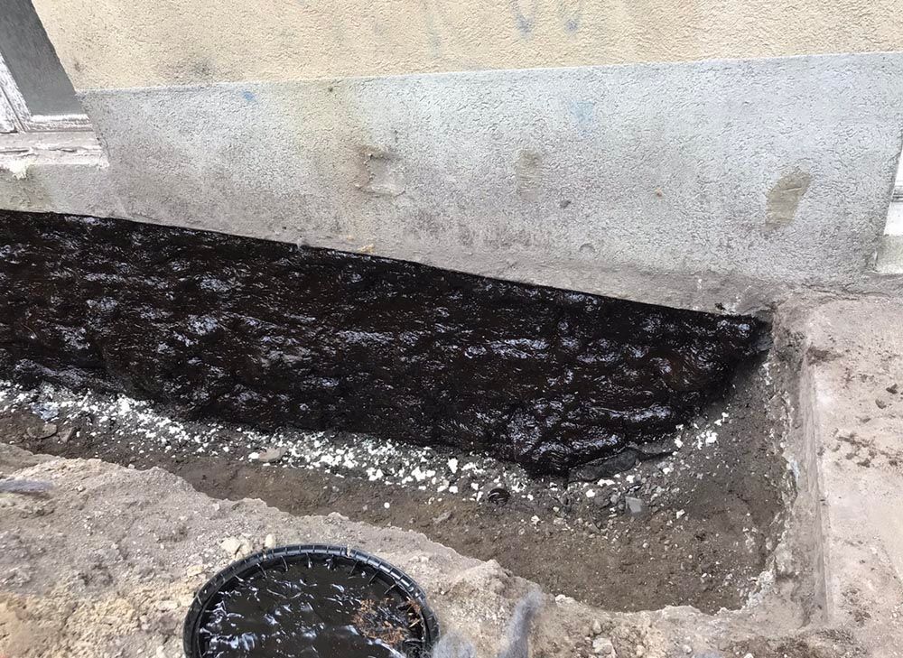 Un seau de liquide noir est posé sur un tas de terre.