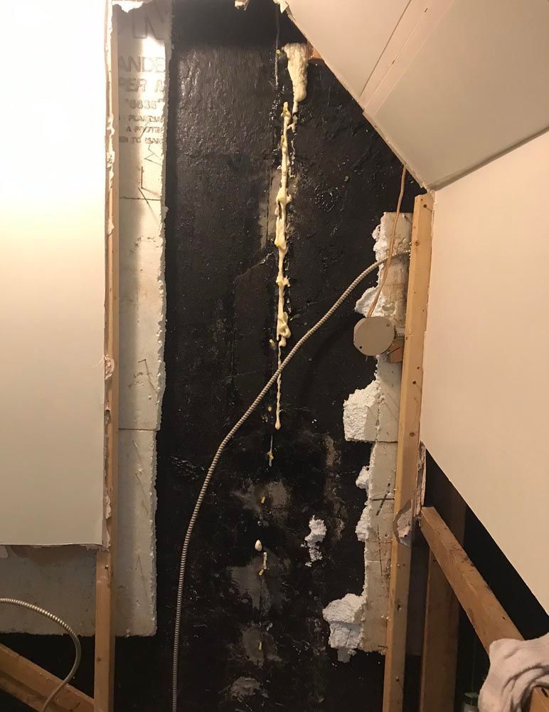Un tuyau sort d'un trou dans un mur.