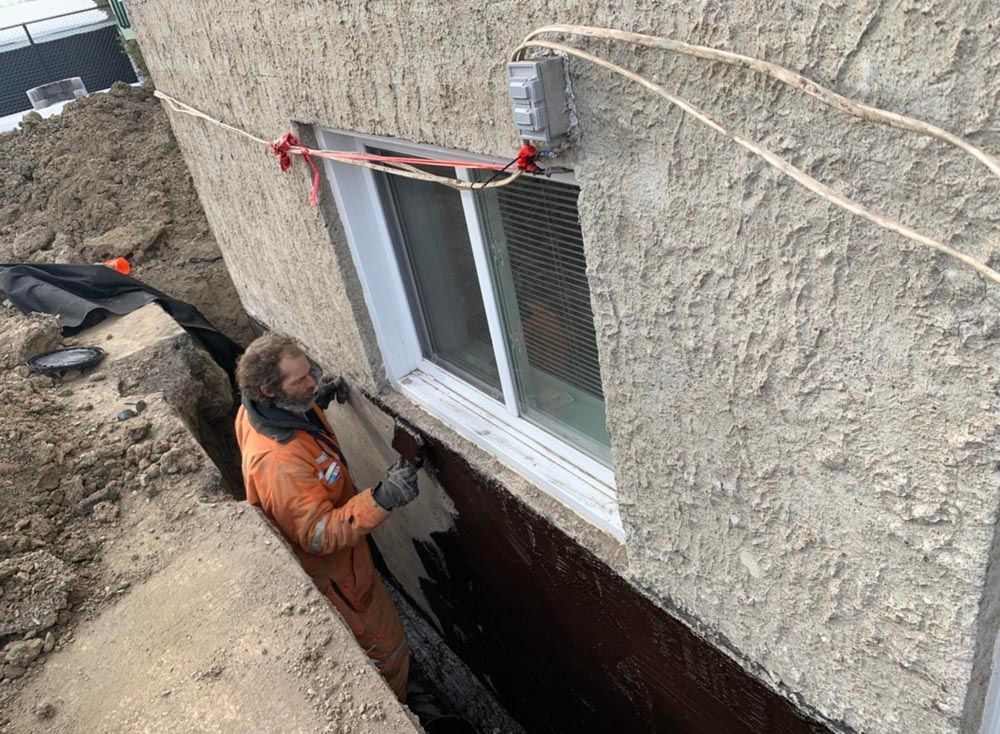 Un homme travaille sur une fenêtre dans un sous-sol.