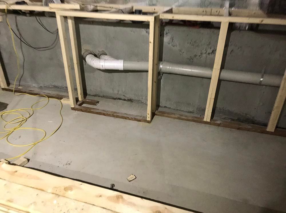 Un mur en béton avec des tuyaux qui en sortent et un plancher en bois.