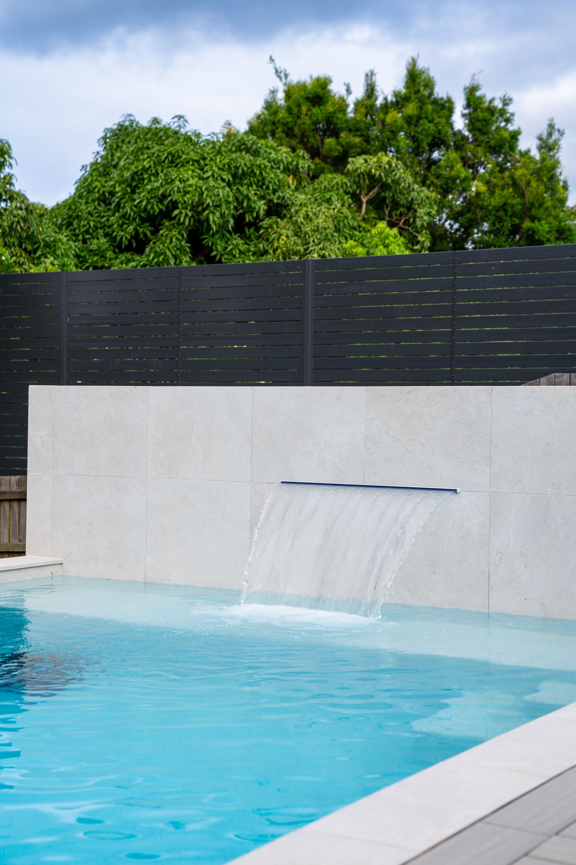Pool Edge With Stainless Steel Ladder, Blue Water, and Beige Tile — Concrete Pool Projects in River Ranch, QLD
