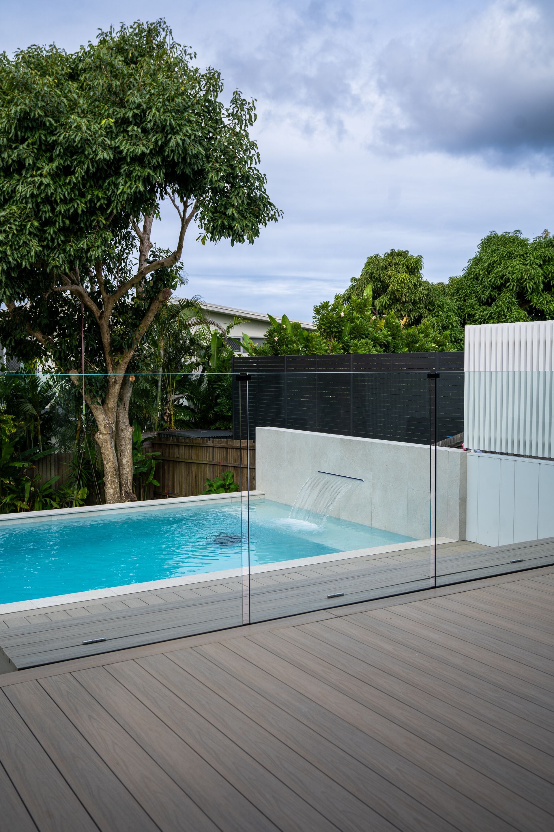 Calm Water Reflecting a Tree-lined Shore Under a Clear Blue Sky — Concrete Pool Projects in Boyne Island, QLD