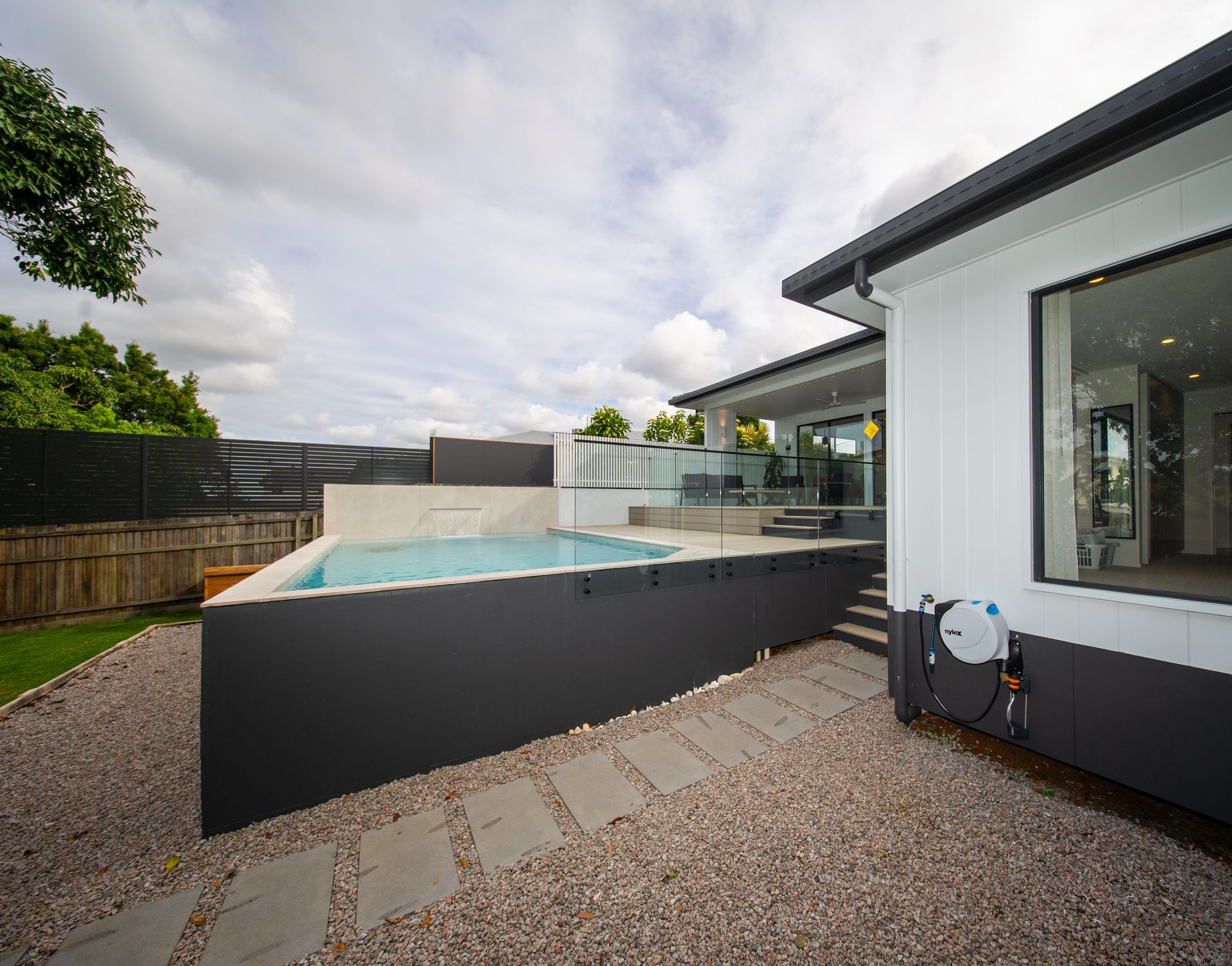 Outdoor Swimming Pool With Spa, Wooden Deck, Trees, and a Covered Patio — Concrete Pool Projects in River Ranch, QLD