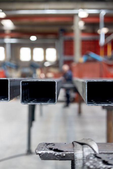 In una fabbrica, un sollevatore industriale con protezioni di sicurezza rosse e parapetti gialli.