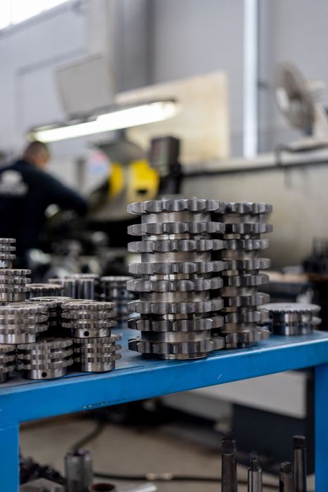 Macchinari industriali in un magazzino, con pannelli impilati rossi e telai di supporto gialli sotto un tetto con lucernario.