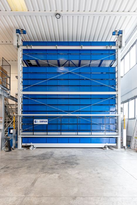 Montacarichi industriale rosso con scaffali rossi impilati in un interno simile a un magazzino.
