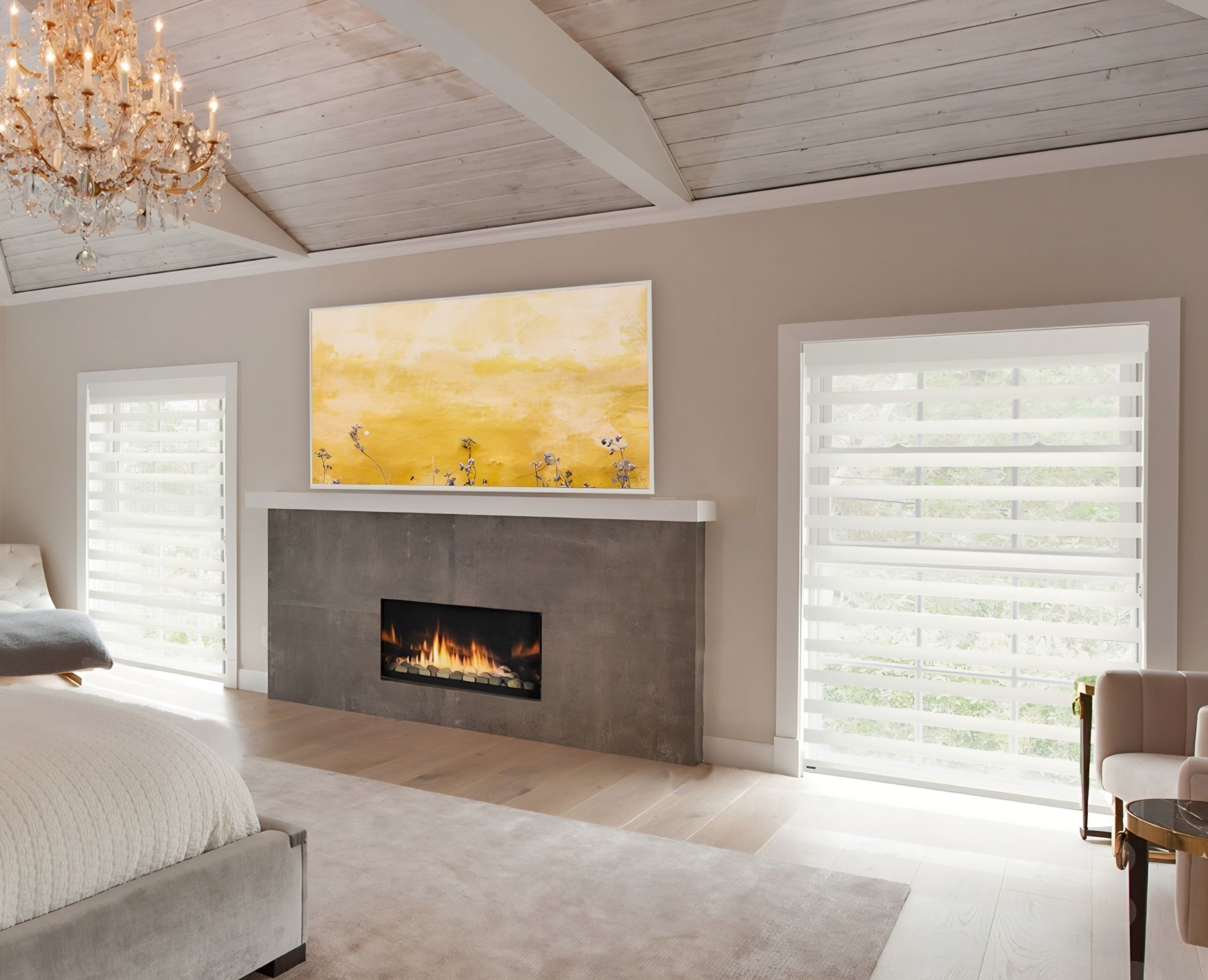 Spacious bedroom with fireplace, yellow artwork, and large windows with layered blinds.