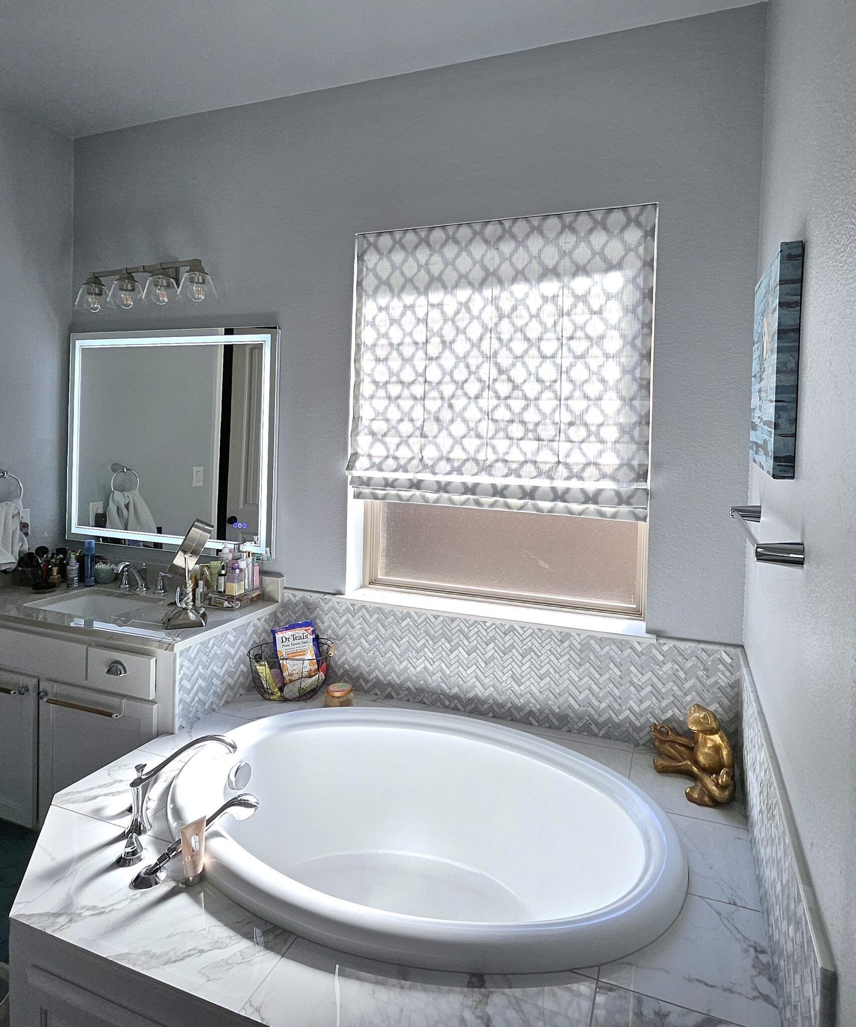 Bathroom with oval bathtub, window, vanity, and decorative tile accents.